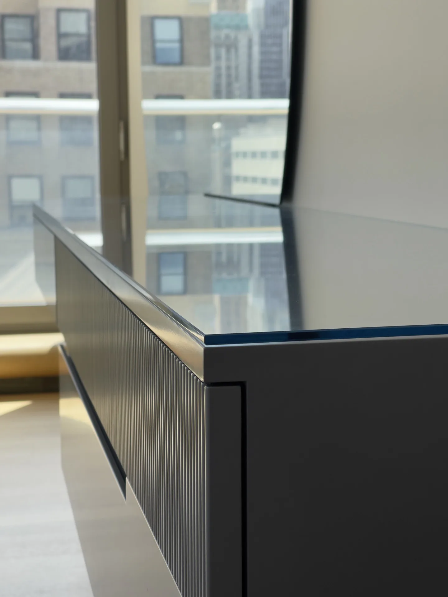 Fluted drawer front meeting the glass top of the floating console, Tribeca outside the window