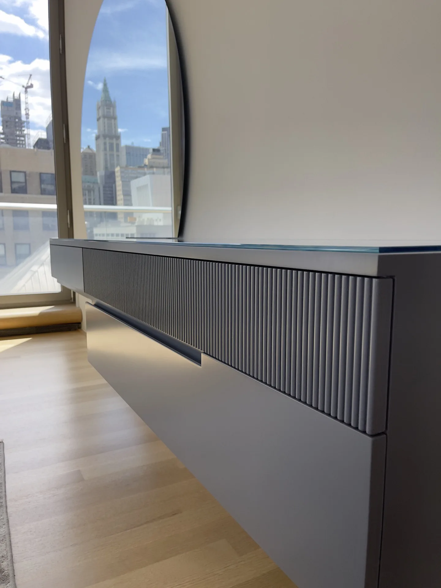 Hardwood fluted front and glass top of the bespoke floating console, Woolworth Building through the window