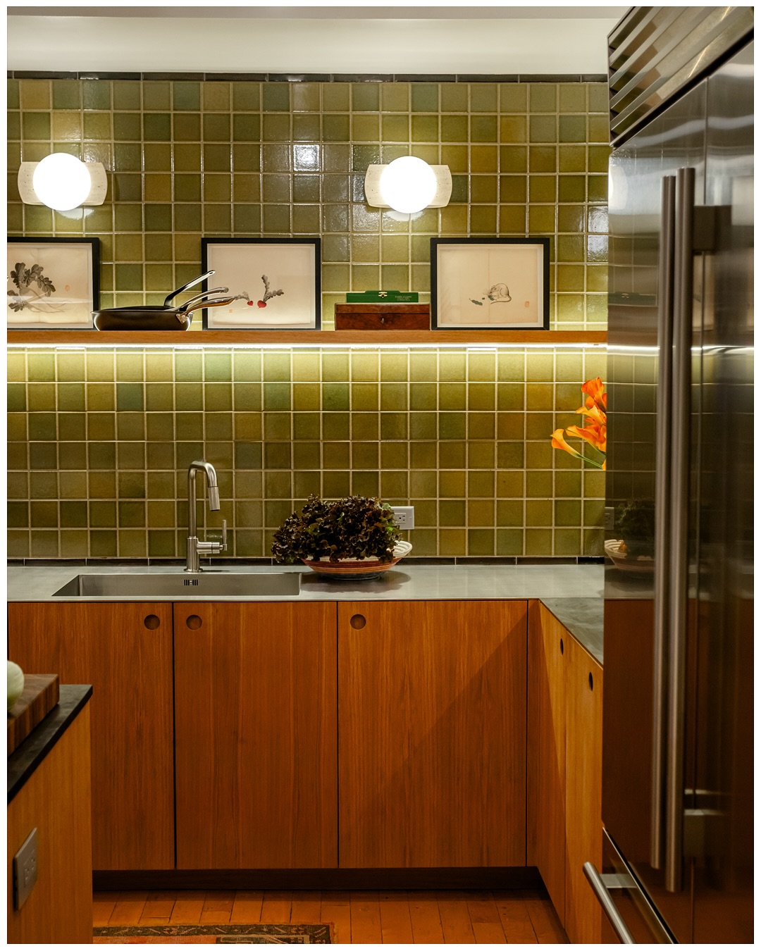Sink run with wood cabinetry, green tile, and an integrated stainless refrigerator