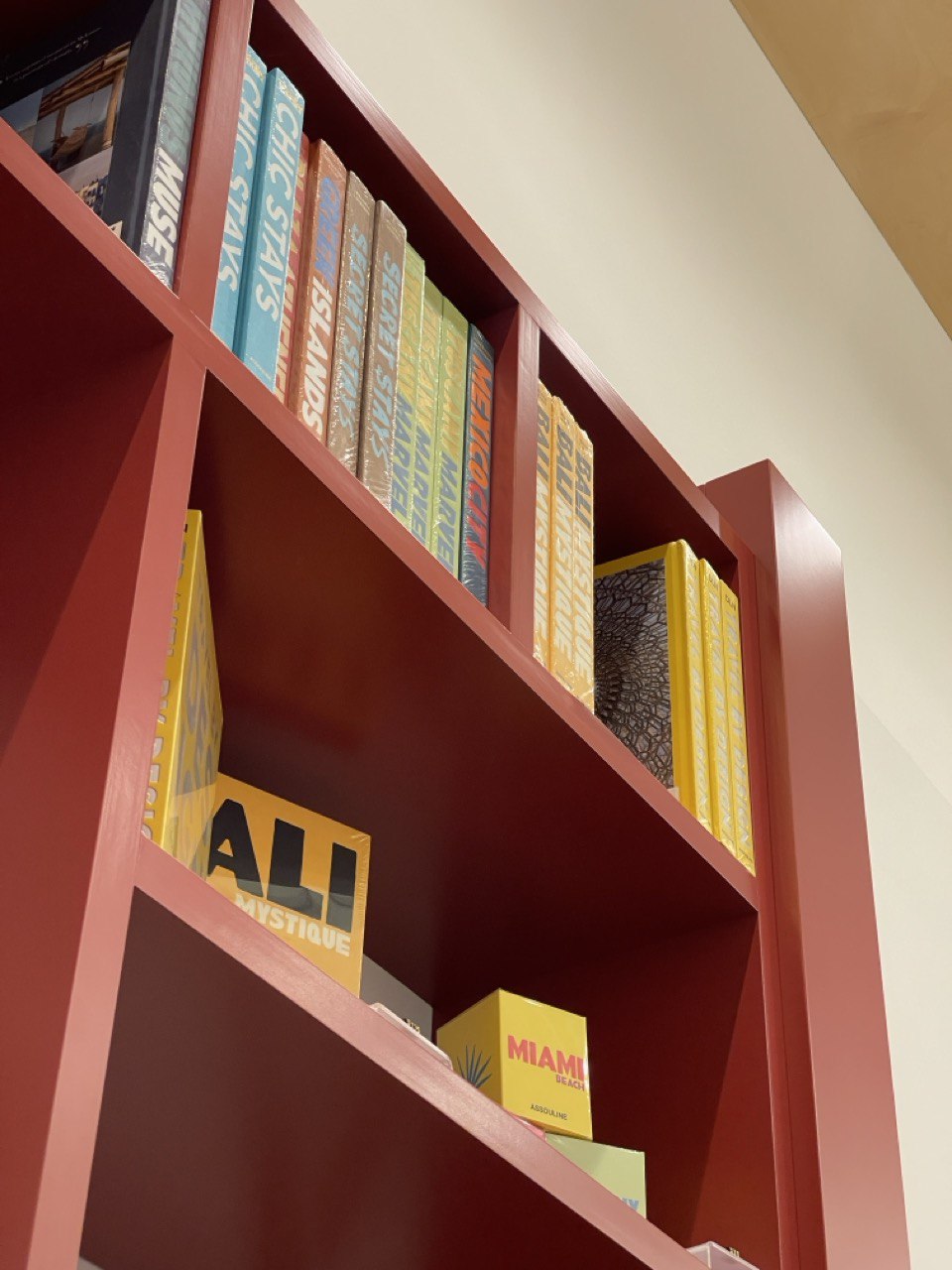 Angled terracotta bookshelf filled with colorful travel guides