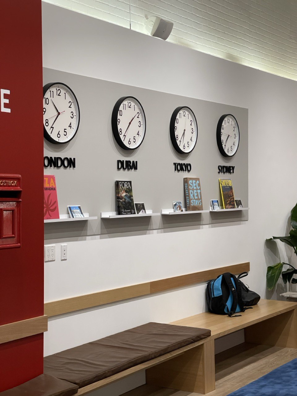 World-clock wall reading London, Dubai, Tokyo, and Sydney above a built-in wood bench