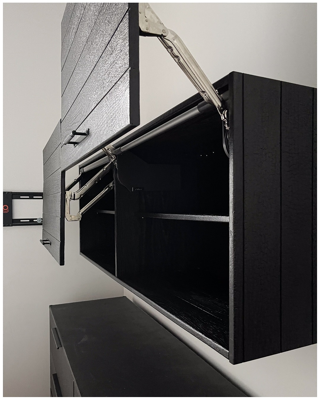 Open wardrobe interior with a chrome hanging rail, a glass shelf, and integrated lighting