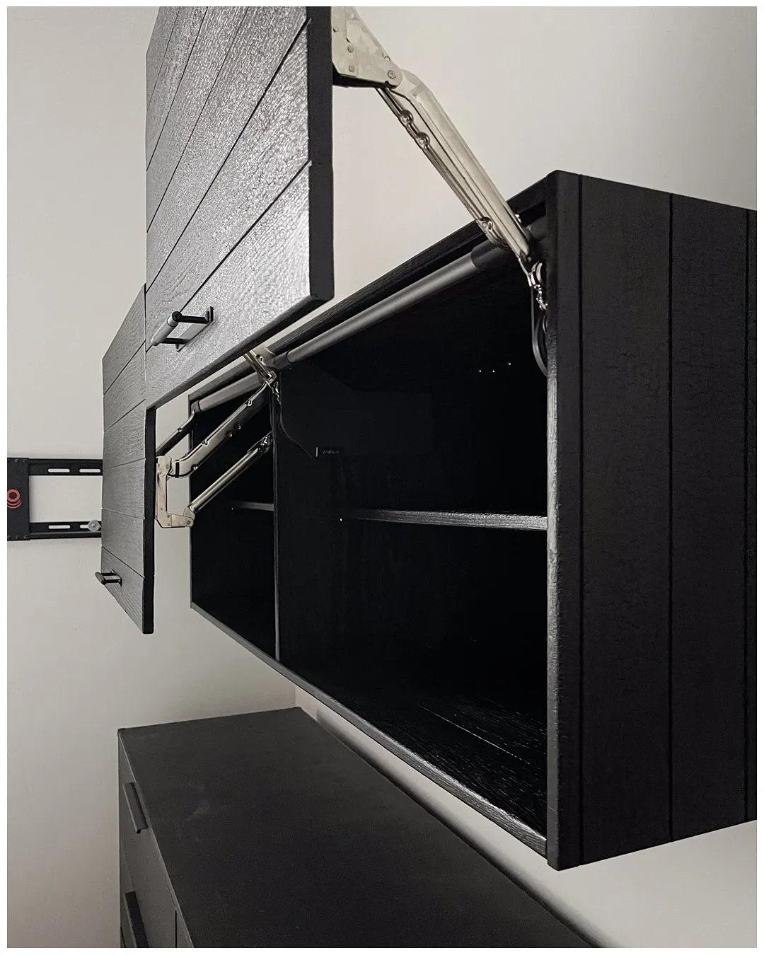 Open wardrobe interior with a chrome hanging rail, a glass shelf, and integrated lighting