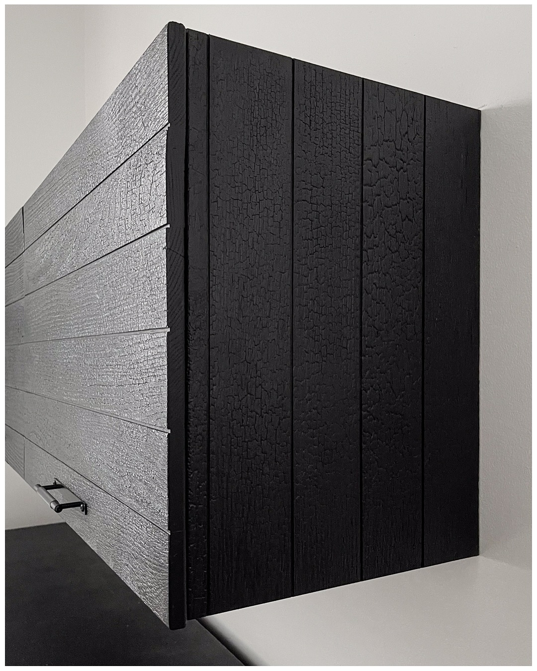 Close-up of the charred wardrobe end, the burned grain cracked into a deep alligator-skin texture