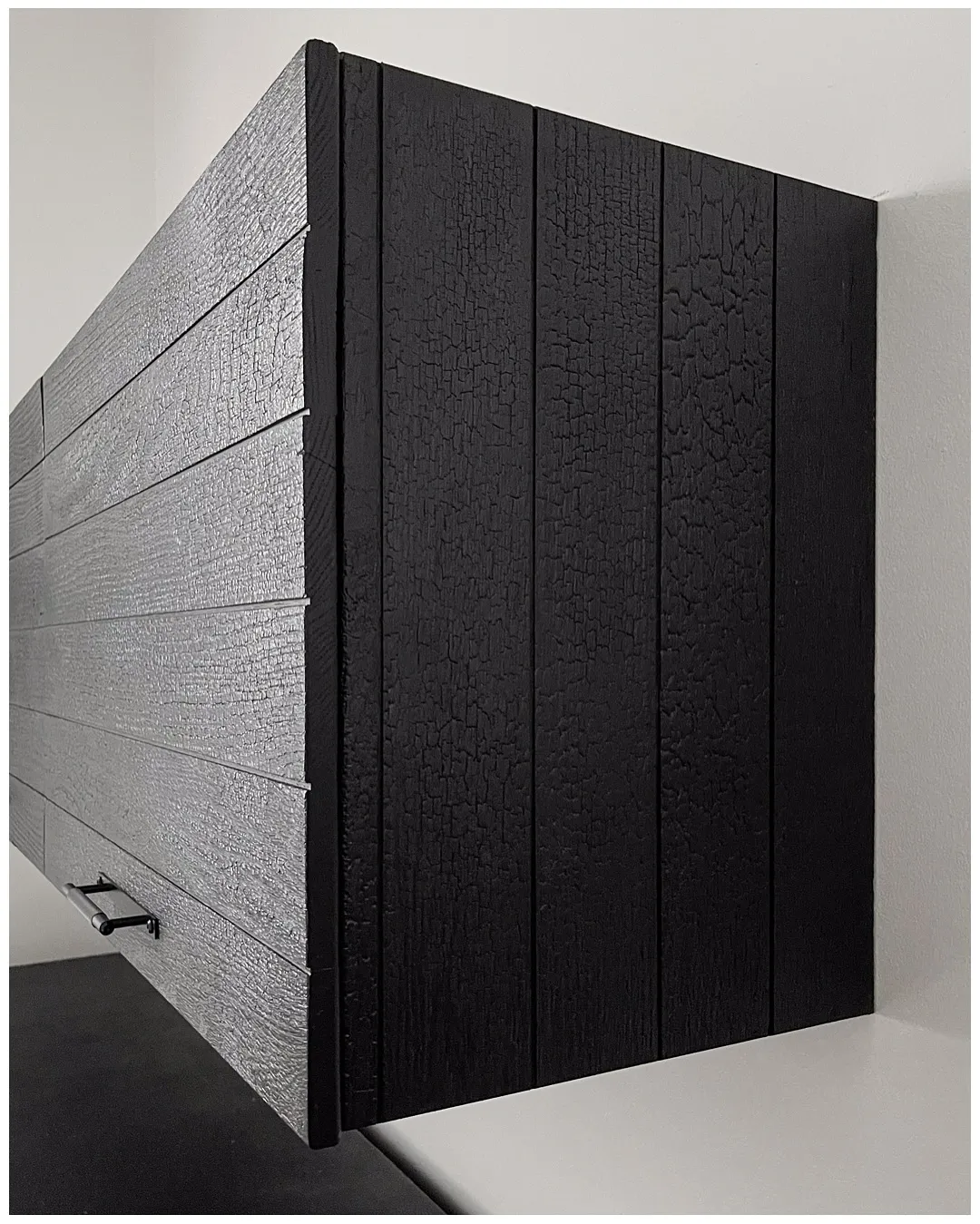 Close-up of the charred wardrobe end, the burned grain cracked into a deep alligator-skin texture