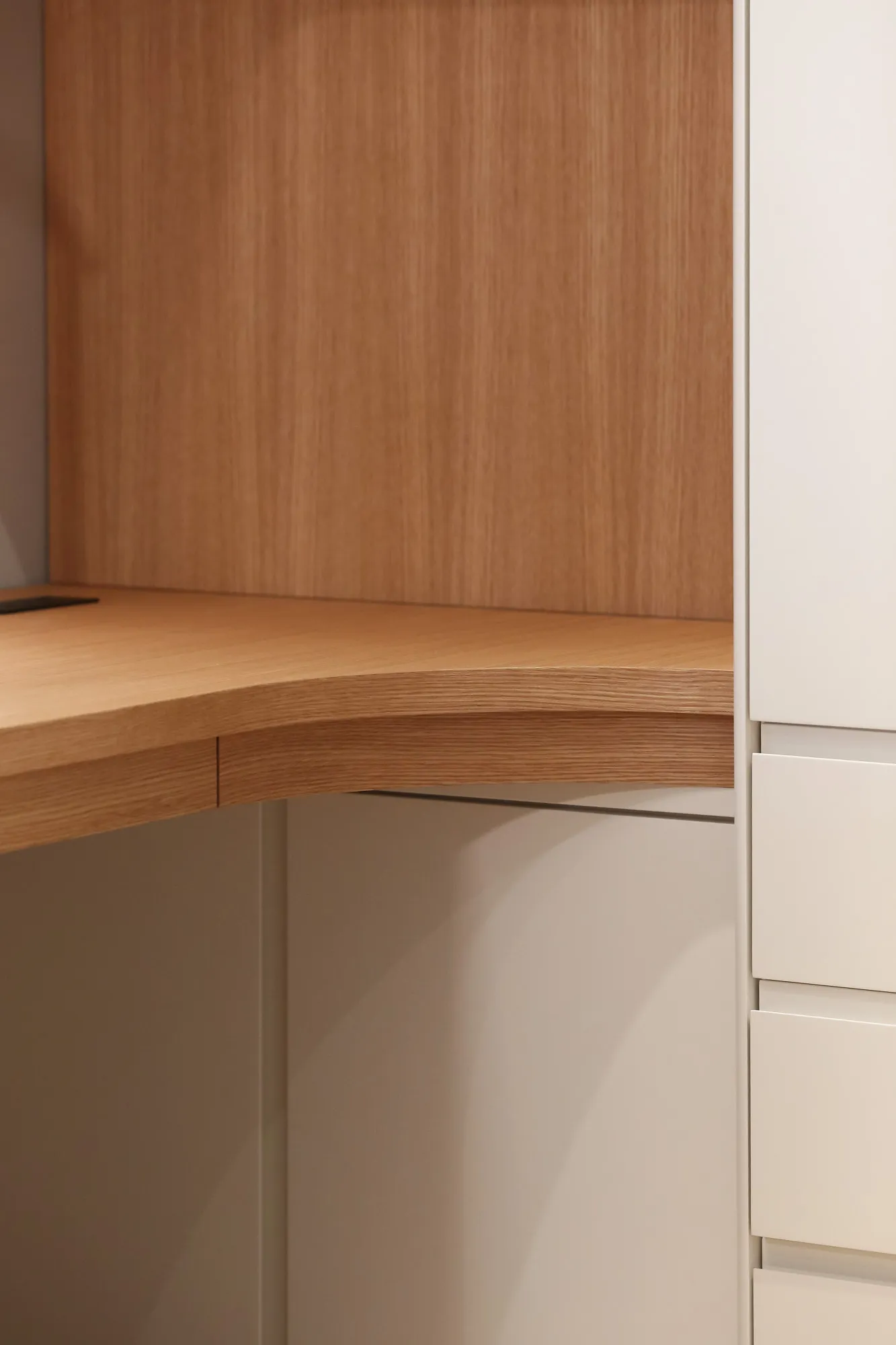 The curved oak edge where the desk meets the painted carcass